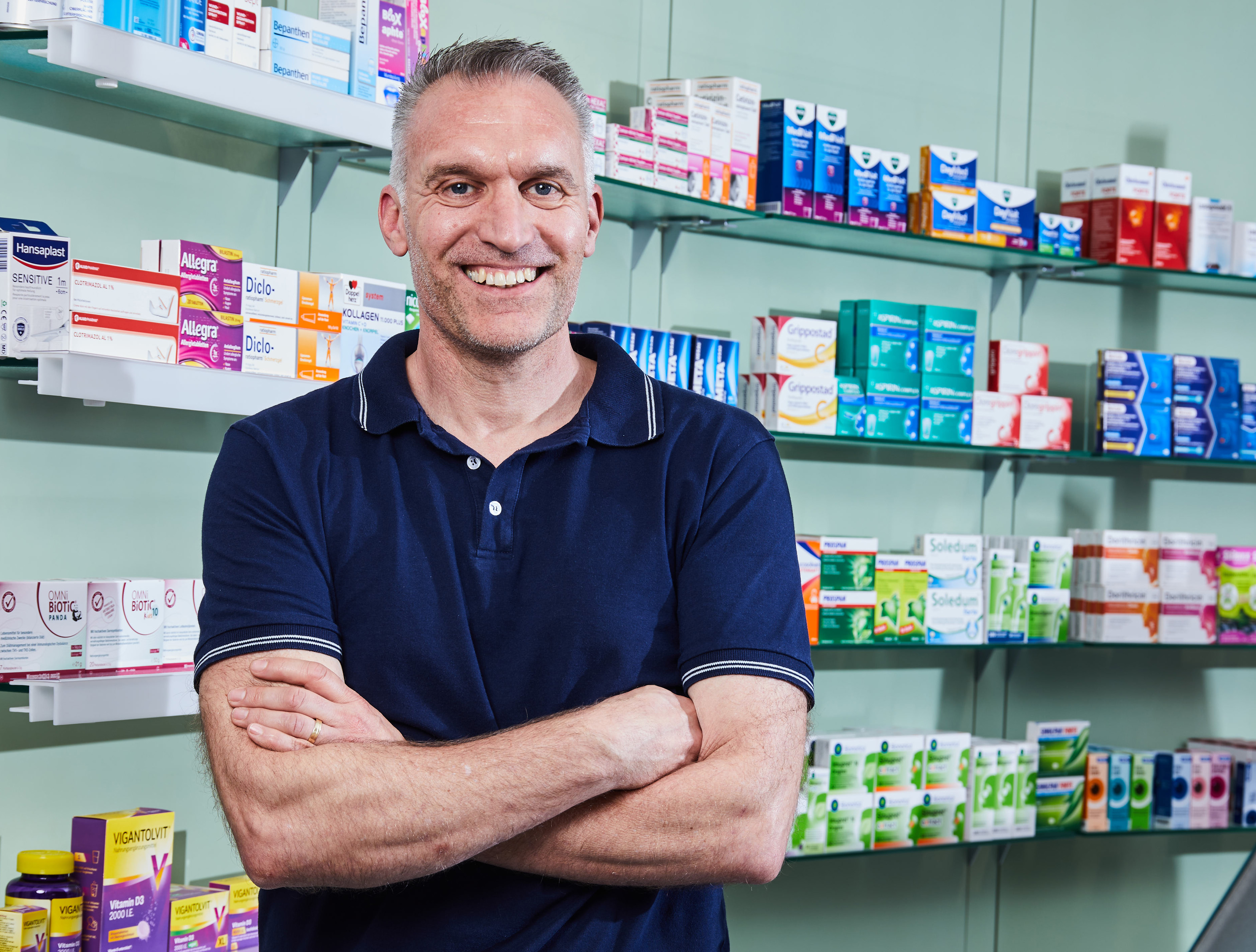 Moderne Innenansicht der Löwen-Apotheke, Inhaber steht vor einem Medikamentenregal.